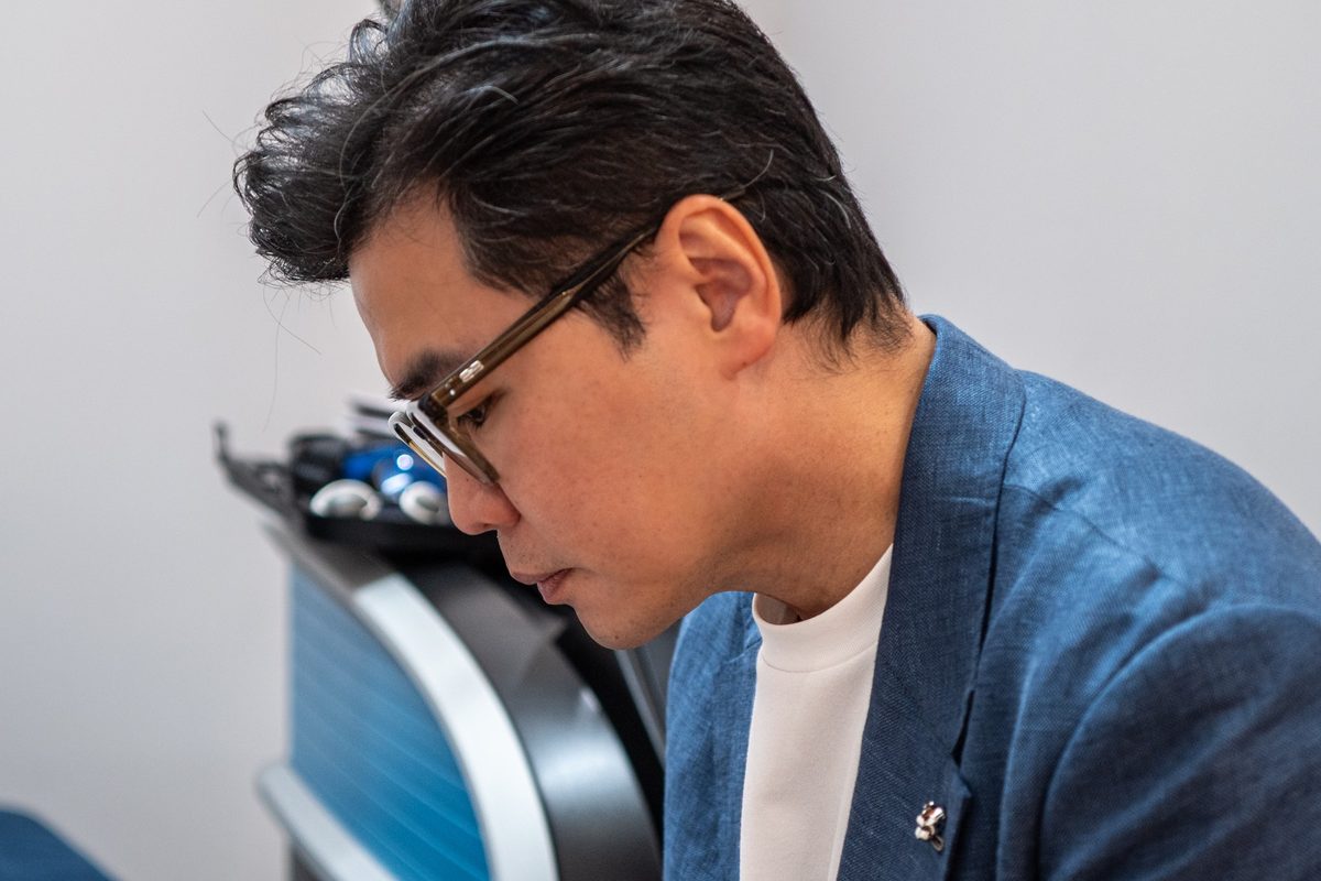 Dr Ong Jin Khang at his consulting workstation, reviewing notes in natural daylight, no patient visible