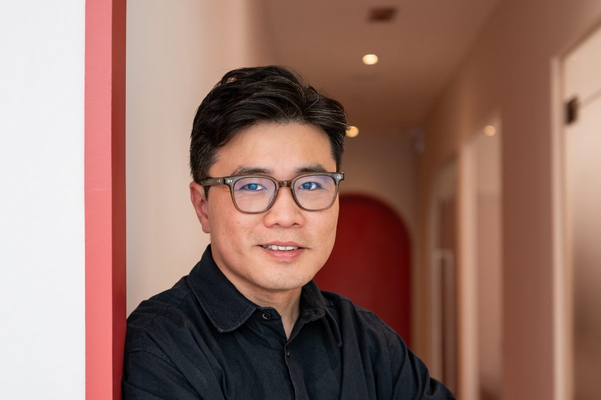 Dr Ong Jin Khang standing in the red-arch corridor of The Retreat Clinic, arms crossed, in soft natural light, no device or treatment in progress