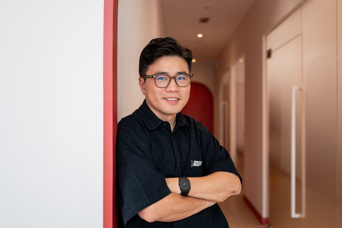 Dr Ong Jin Khang standing in the corridor of The Retreat Clinic in Setia Alam, wearing a white coat, photographed in natural light
