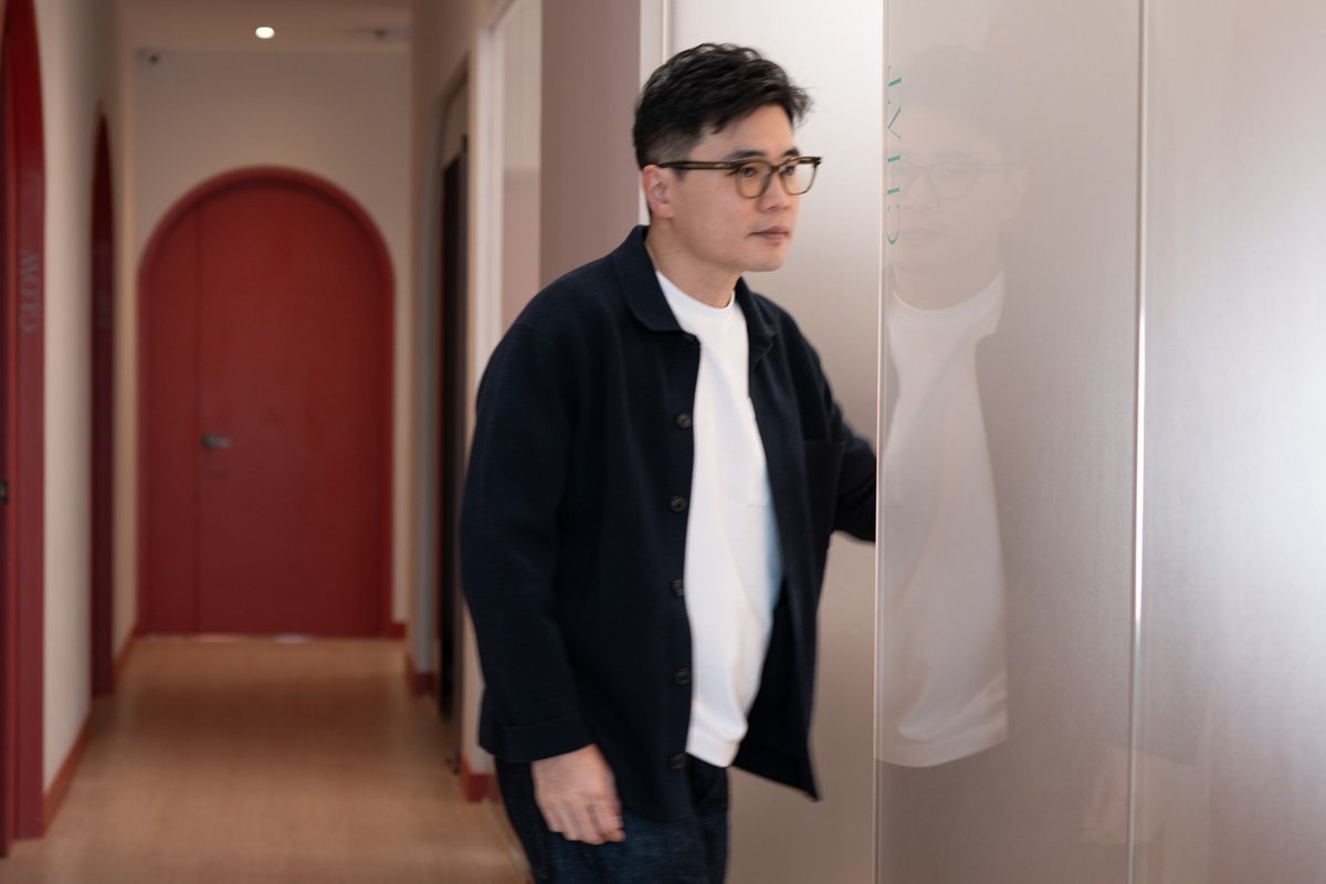 Dr Ong Jin Khang walking alone along a clinic corridor, seen from behind, in contemplative stride