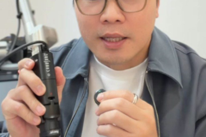 Dr Ong Jin Khang seated and holding a device mid-explanation in a clinical setting, no patient in frame