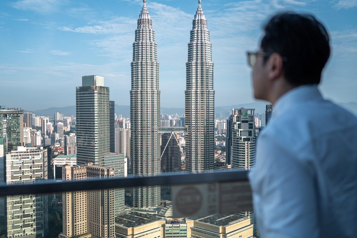 Dr Ong Jin Khang seen from behind in daylight, looking out over a city skyline with two towers standing side by side, no device or treatment in frame