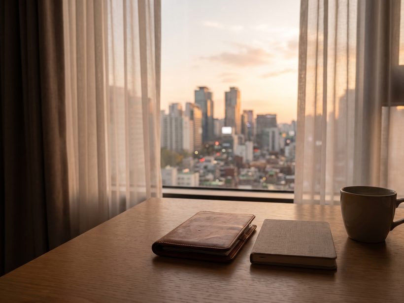 A passport, a small notebook and a pair of reading glasses on a pale linen cloth beside a window in soft daylight, a calm still life with no text, faces, needles or packaging