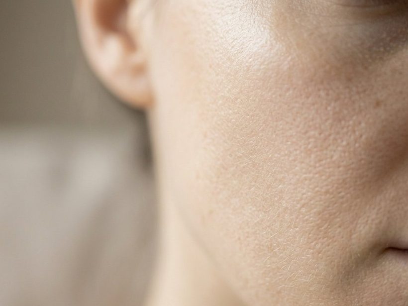 Close-up of a woman's cheek and jawline in natural daylight, skin undisturbed and calm