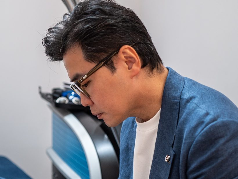 Dr Ong Jin Khang at his consulting workstation, reviewing notes in natural daylight, no patient visible