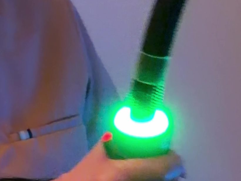 The OndaPro handpiece glowing green against a clinical background, the applicator ring in sharp focus