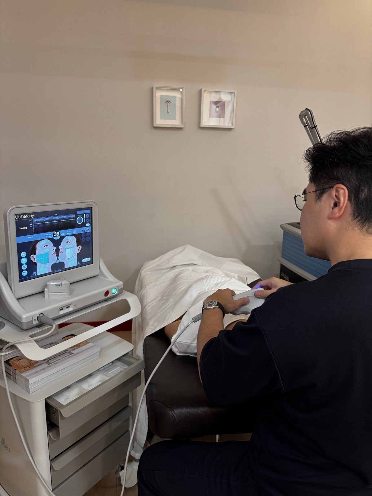 Dr Ong delivering Ultherapy: the transducer on the jawline, the console tracking depth and dose as each line is placed.