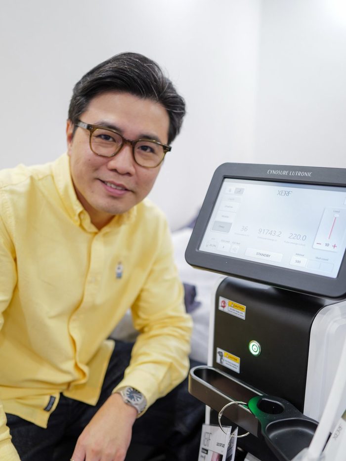 Dr Ong Jin Khang standing beside the XERF console at a clinic overseas